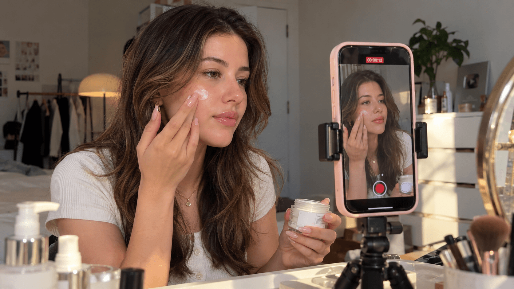 Young woman applies face cream to her cheek while filming a beauty tutorial.