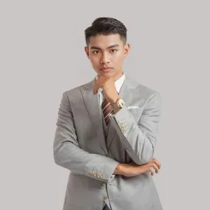 Young man in a gray suit, looking confident with hand on chin.